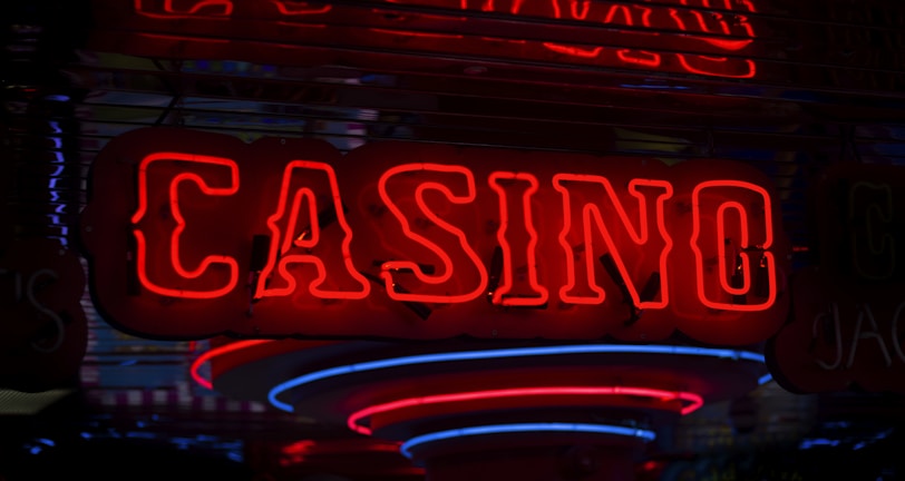 Neon lights display the word 'CASINO' in bright red, standing out against a dark background. The vibrant glow reflects a lively and bustling atmosphere.